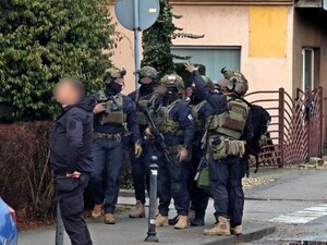 Policjanci i służby ratunkowe stoją przy ulicy.