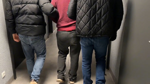 Mężczyzna prowadzony przez policjantów.