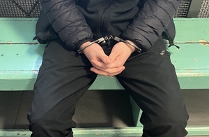 Zatrzymany w kajdankach siedzi na ławce.