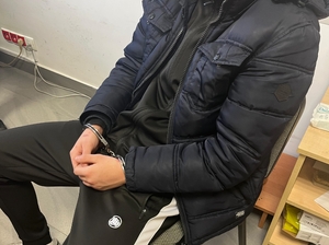 Zatrzymany w kajdankach siedzi na krześle.