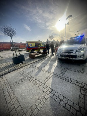 Funkcjonariusze policji, straży i ratownicy przy radiowozie i karetce.