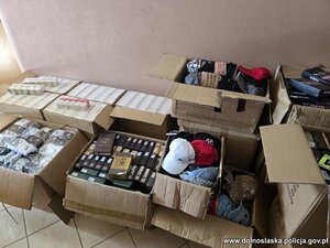 na podłodze rozłożone są kartony i worki z nielegalnym tytoniem, papierosami i odzieżą.
