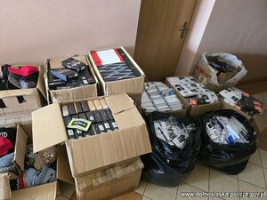 na podłodze rozłożone są kartony i worki z nielegalnym tytoniem, papierosami i odzieżą.