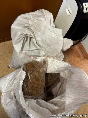 na podłodze rozłożone są kartony i worki z nielegalnym tytoniem, papierosami i odzieżą.