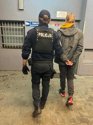 policjanci prowadzą zatrzymanych, stoją na parkingu.