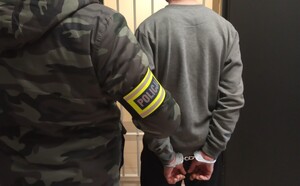 Policjant prowadzi zatrzymanego.