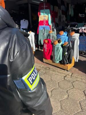 ubrania, torby porozkładane na ziemi. policjanci przeglądają towary.