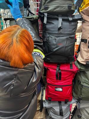 ubrania, torby porozkładane na ziemi. policjanci przeglądają towary.