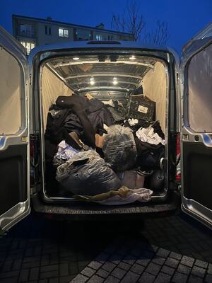 bluzki, kurtki, czapki i torby porozkładane na podłodze i w kartonach.