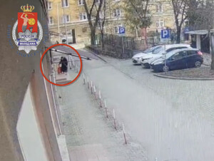 Starsza pani w chodząca do klatki w bloku - zdjęcie z monitoringu.