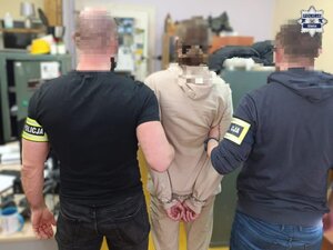 Policjanci prowadzą zatrzymanego. Pobierają odciski palców. pieniądze rozłożone na stole.