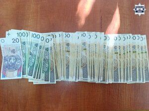 Policjanci prowadzą zatrzymanego. Pobierają odciski palców. pieniądze rozłożone na stole.