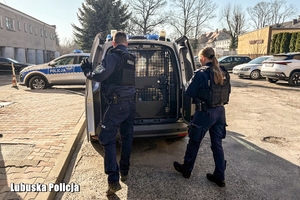 Dwoje policjantów przy radiowozie.