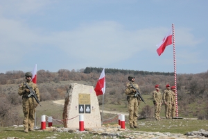 Trzech żołnierzy przy tablicy pamiątkowej.