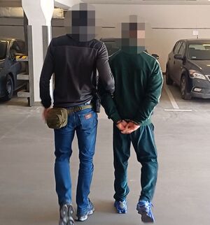 Policjant prowadzi zatrzymanego.