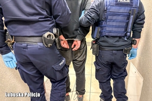 dwóch policjantów prowadzi zatrzymanego.