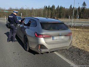 Policjant kontroluje kierowcę siedzącego w samochodzie osobowym.