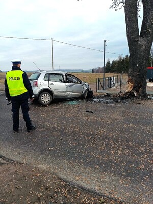 Funkcjonariusz stoi obok rozbitego samochodu.