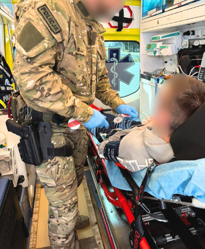 Funkcjonariusz z Samodzielnego Pododdziału Kontrterrorystycznego Policji w Szczecinie stoi w karetce przy noszach, na których leży nastolatek po ataku epilepsji.