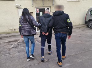 policjanci prowadzą zatrzymanego.