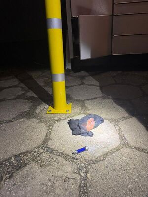 Słupek i fragment otwartego paczkomatu.