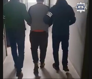 policjanci prowadzą zatrzymanego.