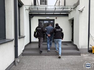 dwóch policjantów prowadzi zatrzymanego.