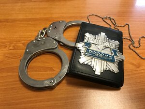 odznaka policyjna i kajdanki leżą na stole.