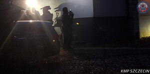 Pora nocna policyjni kontrterroryści przy aucie przed budynkiem.