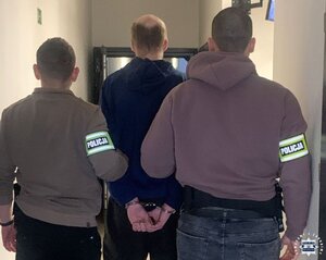 Dwaj policjanci prowadzą zatrzymanego.