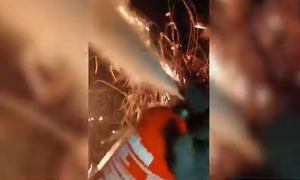 kadr z kamerki nasobnej policjanta. policjant gasi gaśnicą pożar traw.