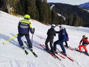 Polski i włoski policjant podczas rozmowy z narciarzami na soku.