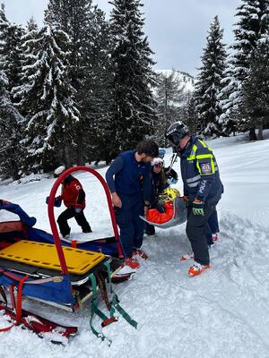 Policjanci i ratownicy przenoszą osobę na skuter.