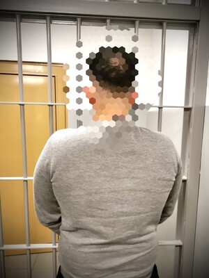 Stojący tyłem zatrzymany mężczyzna.