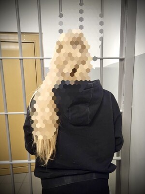 Stojąca tyłem zatrzymana kobieta.