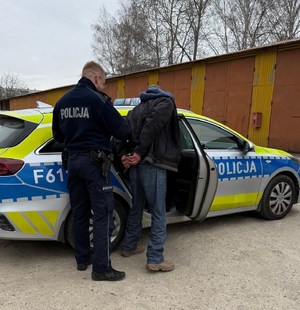 Policjant prowadzi zatrzymanego.