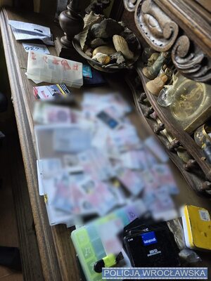 na stole porozkładane karty sim, telefony, w reklamówkach, widać telefony i pieniądze.