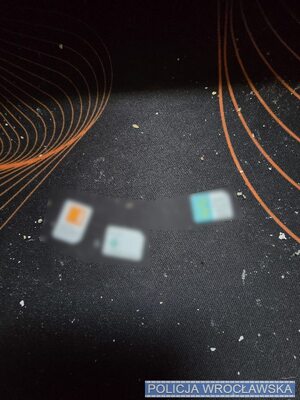 na stole porozkładane karty sim, telefony, w reklamówkach, widać telefony i pieniądze.