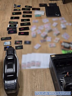 na stole porozkładane karty sim, telefony, w reklamówkach, widać telefony i pieniądze.