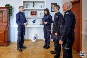 Dwoje policjantów w Gabinecie Komendanta Wojewódzkiego Policji w Kielcach przyjmuje od szefa podziękowania. Na zdjęciu z prawej strony widoczny bezpośredni przełożony policjantów.