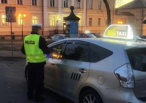 policjant sprawdza trzeźwość kierującego taksówką.