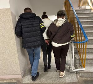 Policjanci prowadzą zatrzymaną.