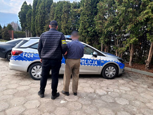 las. Policjant ogląda założone druty. Zatrzymany mężczyzna.