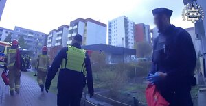 Dwaj policjanci przed blokiem i dwaj strażacy.