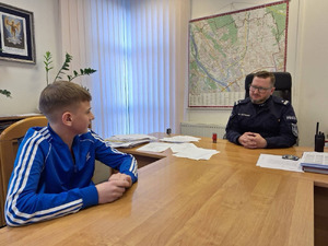 chłopiec wchodzi do komisariatu policji, wita go policjant, chłopiec przymierza stroje policyjne, robi sobie zdjęcia.