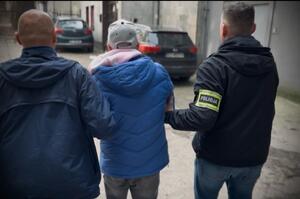 Policjanci prowadzą zatrzymanego mężczyznę.