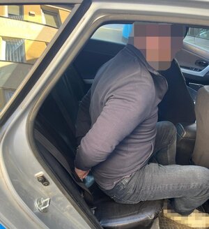 mężczyzna siedzi z tyłu radiowozu.