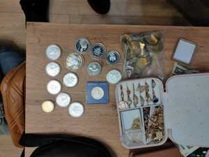 złota biżuteria. monety, kosztowności leżą na stole. Policjanci prowadzą zatrzyamanego.