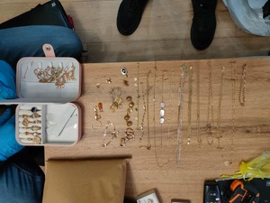 złota biżuteria. monety, kosztowności leżą na stole. Policjanci prowadzą zatrzyamanego.