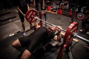 policjant leży na ławce i podnosi ciężary.